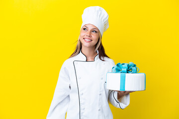 Young Russian pastry chef woman with a big cake isolated on yellow background thinking an idea while looking up