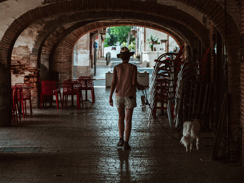 Woman and her dog walking under the arcades of a proven&ccedil;al medieval city