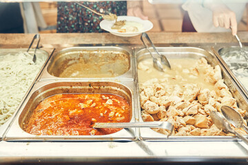 Distribution of food in the dining room. The cook puts goulash on a plate, pork and beef goulash in the foreground. High quality photo