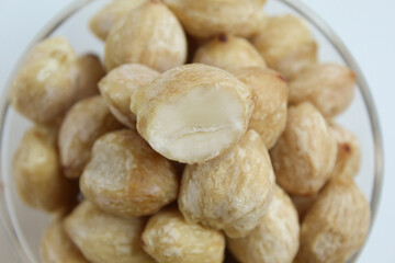 Dried Indonesian Candlenuts, or Kemiri, the seed of Aleurites moluccanus inside a transparant bowl, isolated in white background. Flat lay or top view