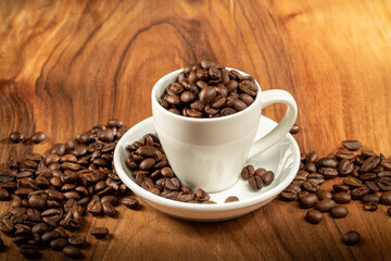 Coffee theme. A ceramic cup filled to the brim with coffee beans stands on a wooden background