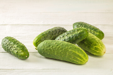 A bunch of fresh cucumbers with pimples on a white wooden table
