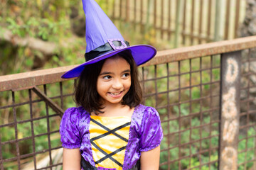 Girl smiling looking to the side dressed as a witch for halloween with hat