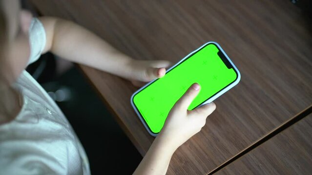 The girl flips through the tape on the smartphone. Green screen, chroma key.