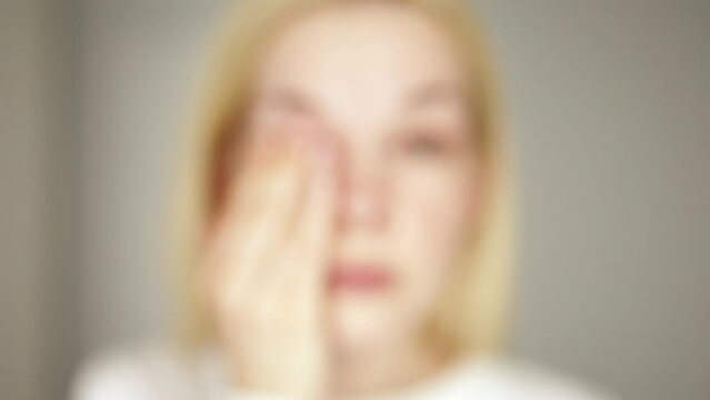 A tired woman takes off her eyeglasses and rubs her eyes with her hands, she sees badly and everything is blurred. Poor vision concept.