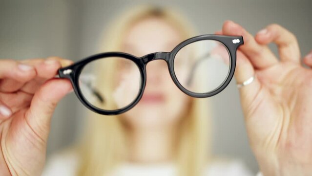 Woman holding eyeglasses in her hands. The concept of vision correction and eye optics.