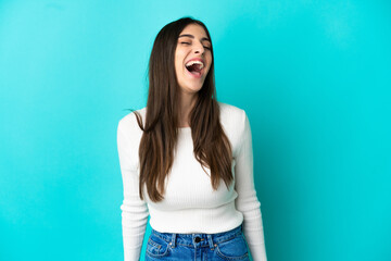 Young caucasian woman isolated on blue background laughing