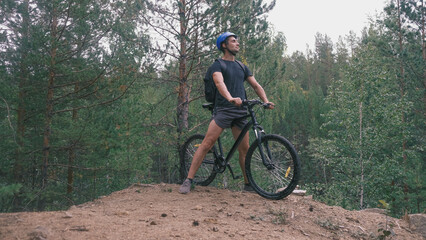 Obraz premium mountain bike.A man in a protective helmet and sports equipment stopped on rough terrain and looks away.Active lifestyle