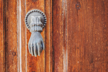 Heurtoir en métal représentant une main sur une vieille porte en bois