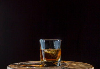 Glass of whiskey with ice on a dark background.