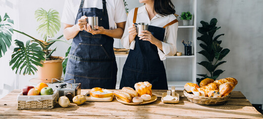 Happy young adult couple making breakfast and drinking coffee together in cozy home kitchen in morning at home. Preparing meal and smiling. Lifestyle, leisure and Love concept.