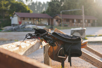 Horse saddle with stirrups on a farm outside, close up