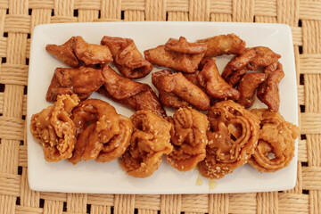 Moroccan chebakias on a white plate in a patio with plants