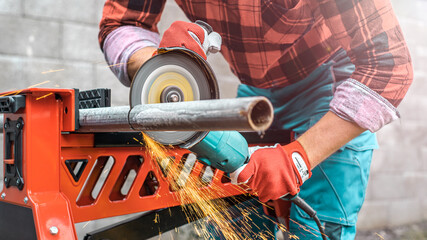 Sawing an iron pipe with an angle grinder.