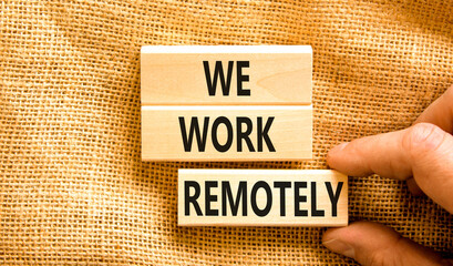 We work remotely symbol. Concept words We work remotely on wooden block. Beautiful canvas table canvas background. Businessman hand. Business we work remotely concept. Copy space.