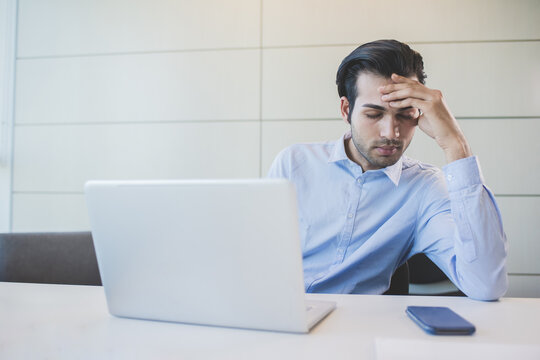 Young indian businessman indoors office working suffering headache