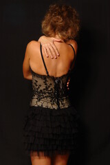 Girl in a corset on a black background - back view
