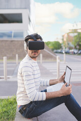 Young indian man using 3D viewer and pc gaming outdoors