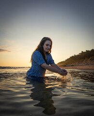 kobieta kąpiąca się w morzu na tle wschodzącego słońca