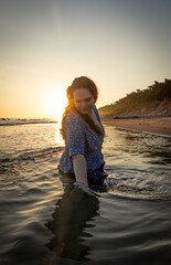 radosna dziewczyna kapiąca się w morzu o wschodzie słońca  - obrazy, fototapety, plakaty