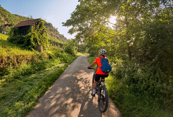 nice woman with electric mountain bike, cycling in moody morning light on the Neckar valley bicycle path near Ludwigsburg, Baden Württemberg, Germany