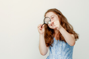 little cute girl examines a puzzle element through a magnifying glass