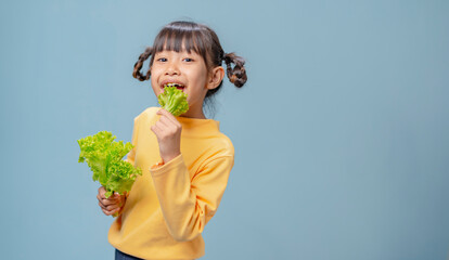 A little girl loves vegetables and is eating vegetables.