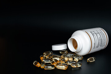Fish oil capsules with jar on black background