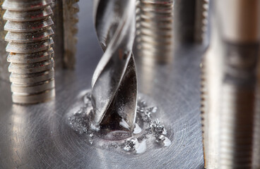 metal drill bit with lubrication oil liquid make holes in steel billet on industrial drilling...