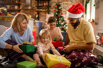Young caucasian family opening presents during christmas and the new year holidays in the living...