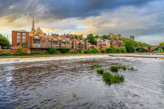 The skyline of the city of Durham including the Romanesque Durham Cathedral and Durham Castlen, now a university, is seen behind the River Wear under a dramatic sky in Durham, England UK.