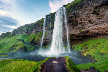 Seljalandsfoss waterfall flowing and lush mountain in summer at Iceland.