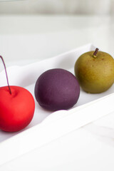 Modern realistic fruit pastries made of chocolate and mousse. Red apple, green apple, blueberry and passion fruit for cafe or restaurant