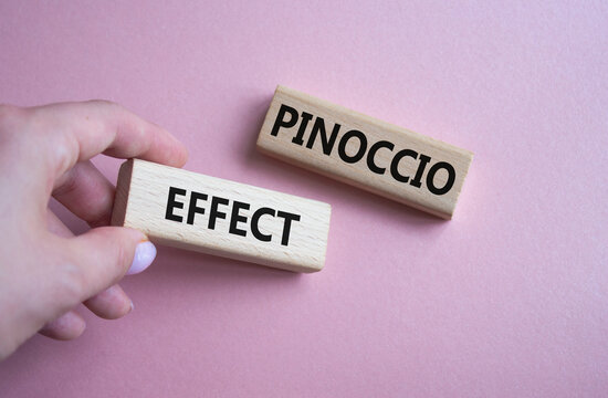 Pinoccio Effect symbol. Concept word Pinoccio Effect on wooden blocks. Businessman hand. Beautiful pink background. Business and Pinoccio Effect concept. Copy space