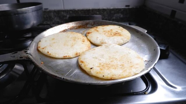 Three arepas are cooked on kitchen pan for breakfast