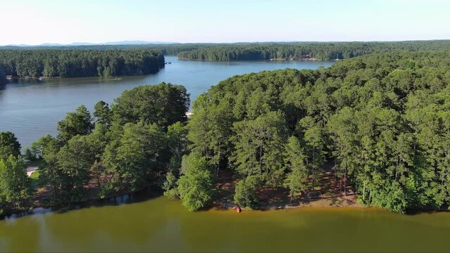 aerial footage of a gorgeous summer landscape at Proctor Landing park with green lake water, trees and grass, boats and people in the water with blue sky and clouds at Lake Acworth in Acworth Georgia