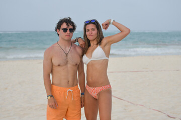 Young couple on the beach showing muscles