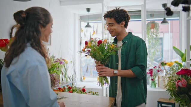 Emotional shopper give flower present gift to beautiful florist woman in store.
