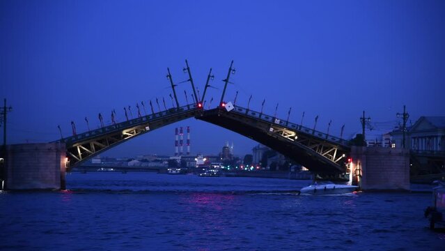 Side view from tour boat on closing bascule bridge at night in Saint Petersburg city, Russia. Real time handheld video. Urban transportation building. Water travel business theme.