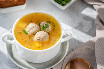 Vegetable soup with meatballs in a white soup cup. Low-calorie soup with herbs and crackers