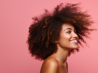 beautiful woman portrait with afro hair in profile smiling on pink background