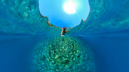 Man snorkeling with 360 degree underwater camera in the beautiful, crystal clear sea at Zuljana beach, Croatia - obrazy, fototapety, plakaty