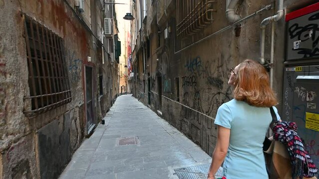Genoa, Liguria, Italy. June 3, 2023. Engaging pov footage walking through the alleys of the historic center, a middle-aged woman precedes us. She explores and discovers Genoa.