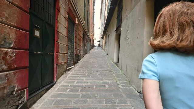 Genoa, Liguria, Italy. June 3, 2023. Engaging pov footage walking through the alleys of the historic center, a middle-aged woman precedes us who grabs our hand and leads us. Follow me concept.