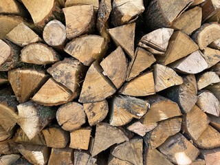 Firewood in a heap,prepared for the winter. Stacked firewood background. Dry textured firewood. Chopped wooden logs. Rustic background. Selective focus.