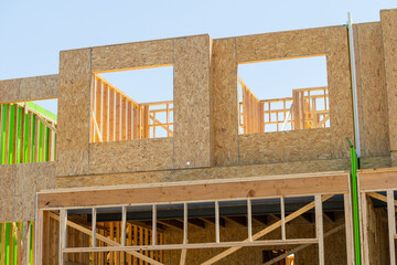 Against the backdrop of a vivid blue sky, the lumber plank accents the house framing in the new...