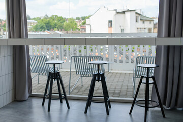 interior of a cozy cafe with a summer terrace and city view. Black and white furniture. Cozy coffee shop atmosphere