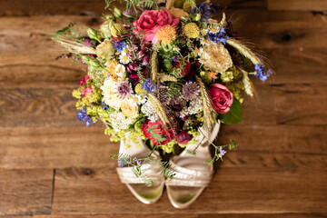 bridal bouquet of field flowers over bridal shoes