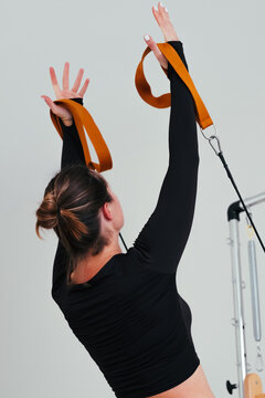 Rear view of a girl doing pilates exercises on a reformer for the upper body.