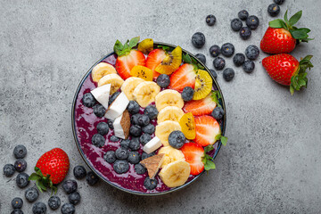 Healthy summer acai smoothie bowl with chia seeds, fresh banana, strawberry, blueberry, cocos, kiwi...